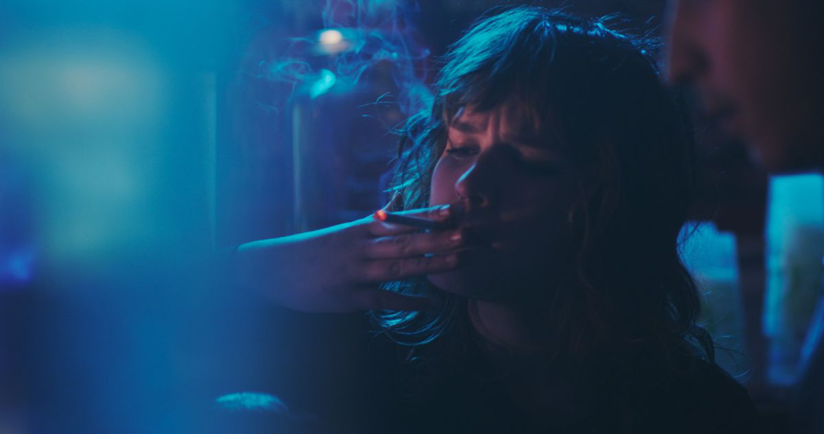 A young person smokes a cigarette in a blue-filtered image from T-Blockers