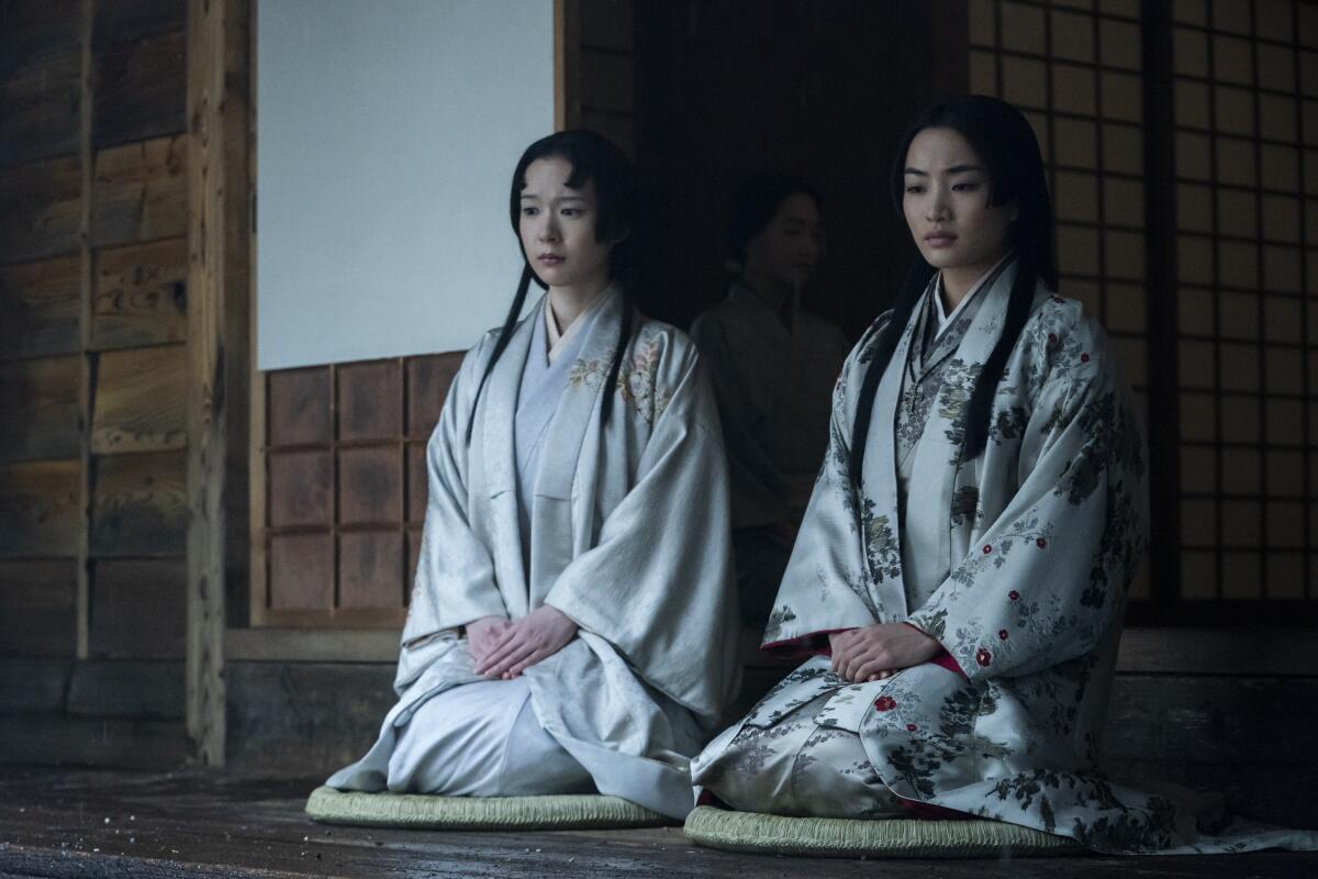 two women in kimono sitting in a hallway