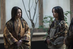 two women in kimono standing in a courtyard