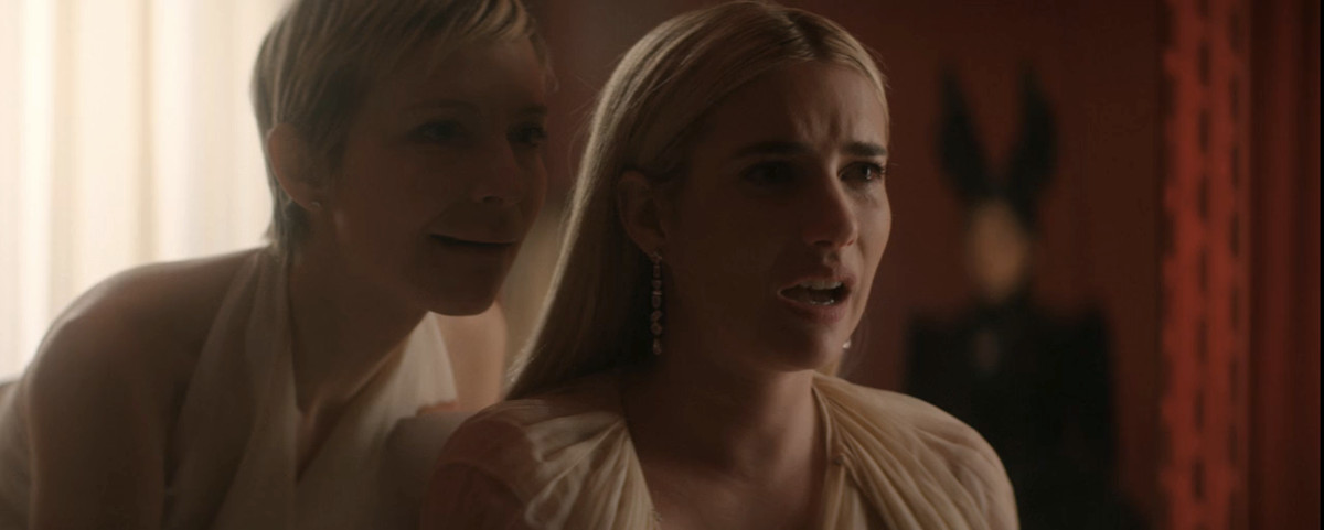 Emma Roberts and a blonde woman in a pixie cut chanting together. 