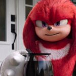 Red haired and purple-eyed Knuckles looks intense holding a pot of coffee on a porch in article about if knuckles tv show sets up sonic the hedgehog three