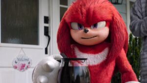 Red haired and purple-eyed Knuckles looks intense holding a pot of coffee on a porch in article about if knuckles tv show sets up sonic the hedgehog three