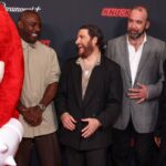Knuckles stands obscured in a red carpet photo with his Knuckles cast of Idris Elba, Adam Pally, Rory McCann and Kid Cudi as they all laugh