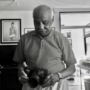 A man looks at a camera that he is holding.