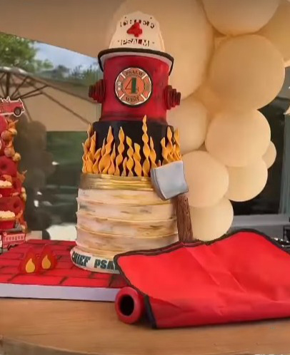 The layered cake was decorated to include a firefighter helmet on top of a red fire hydrant