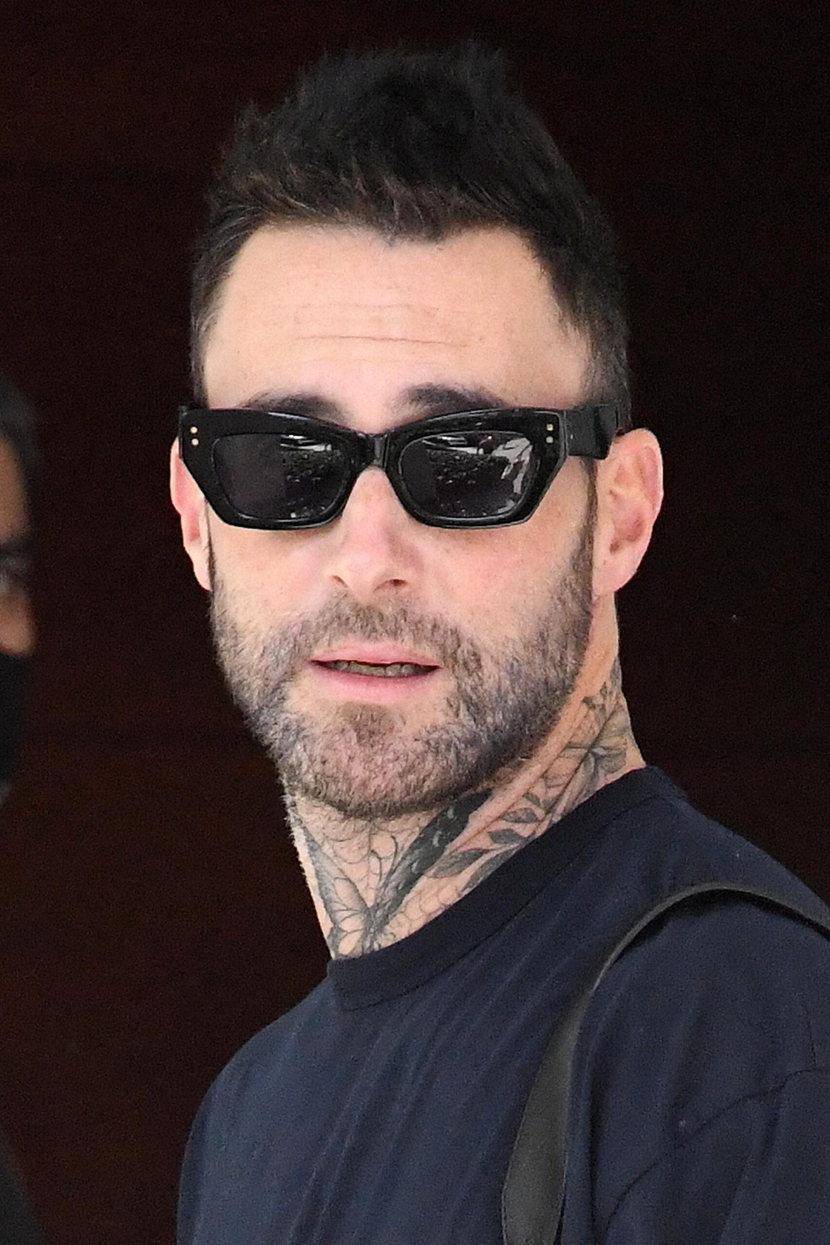 Adam Levine proves his new face tattoo was only temporary as he is seen leaving his hotel with wife Behati Prinsloo in Miami