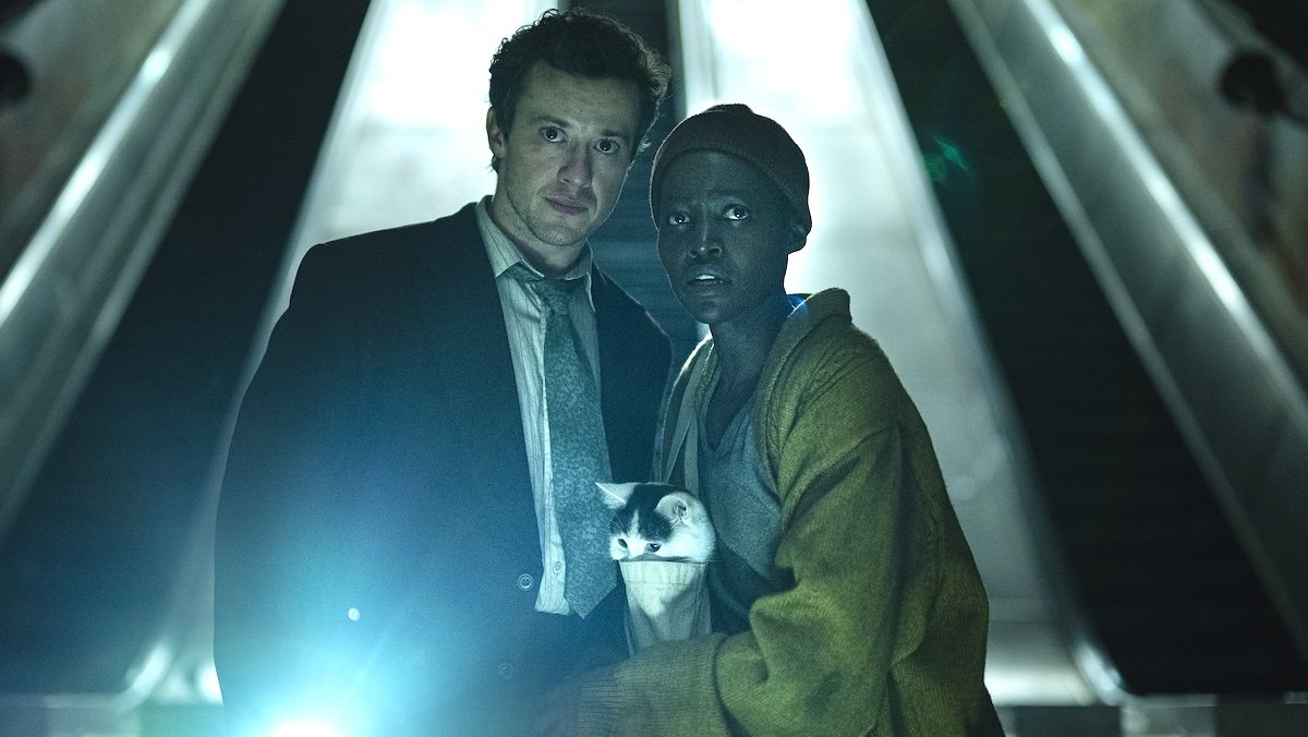 Lupita Nyong’o as “Samira” and Joseph Quinn as “Eric” in A Quiet Place: Day One huddled with a cat and flashnight underground