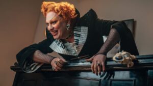 Jinkx Monsoon villain character Maestro leans over the top of a piano in doctor who episode