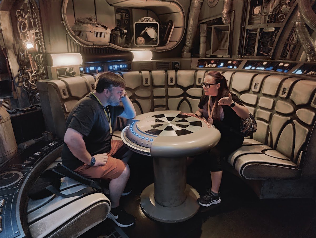 A man and woman inside a replica Millennium Falcon at the Dejarik table