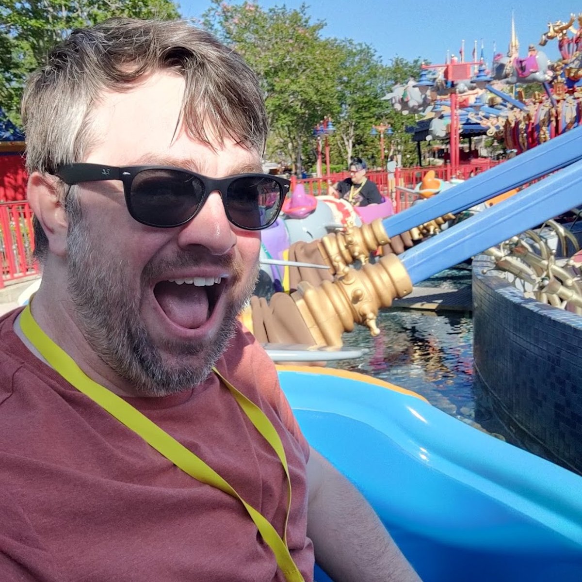 A goofy man with sunglasses smiling while riding Dumbo at Magic Kingdom