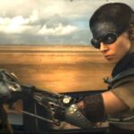 Anya Taylor-Joy on a motorcycle with a shaved head and black on her forehead in Furiosa: A Mad Max Saga