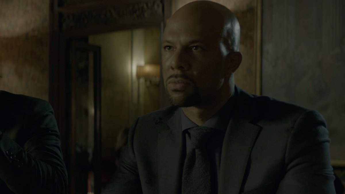Common's Cassian dressed all in black at a bar in John Wick: Chapter 2