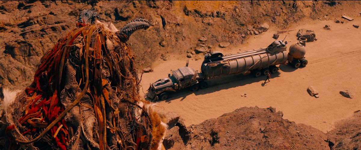 A rock rider peers over a cliff side to look at Furiosa’s War Rig in Mad Max: Fury Road