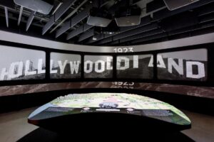 A large tabletop display and the words "Hollywoodland" projected onto the wall behind it in an exhibition.