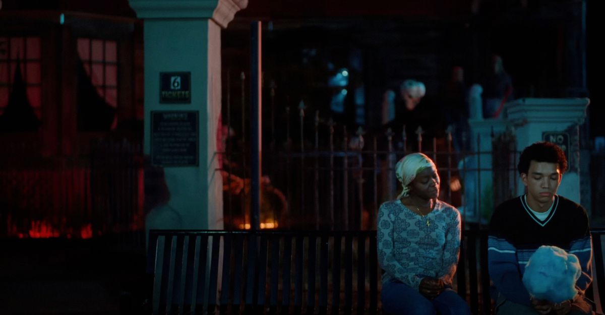 Owen (Justice Smith) and his mother (Danielle Deadwyler) sit outside on a bench together at night in Jane Schoenbrun’s I Saw the TV Glow