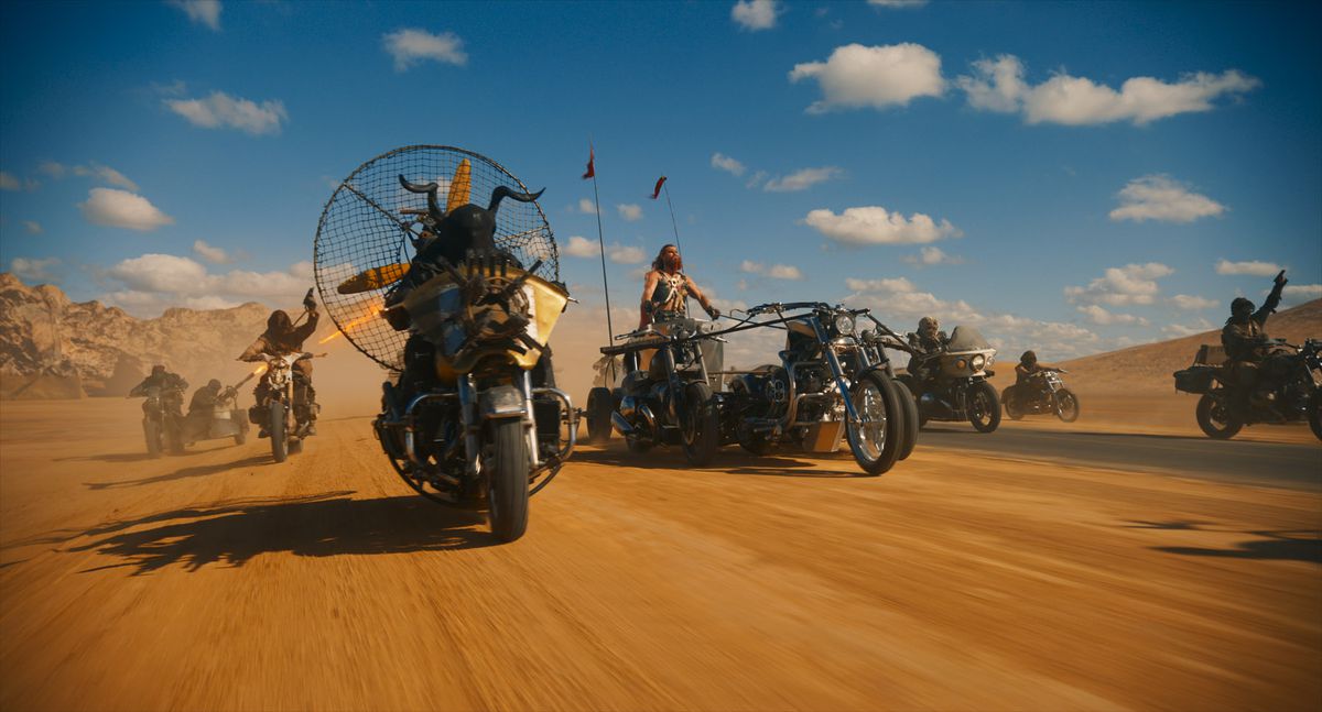 Several character drive through the desert on makeshift vehicles led by Chris Hemsworth in Furiosa the Mad Max spinoff movie