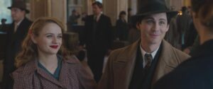 A young man and woman in period clothing smile at someone in a scene from "We Were the Lucky Ones."