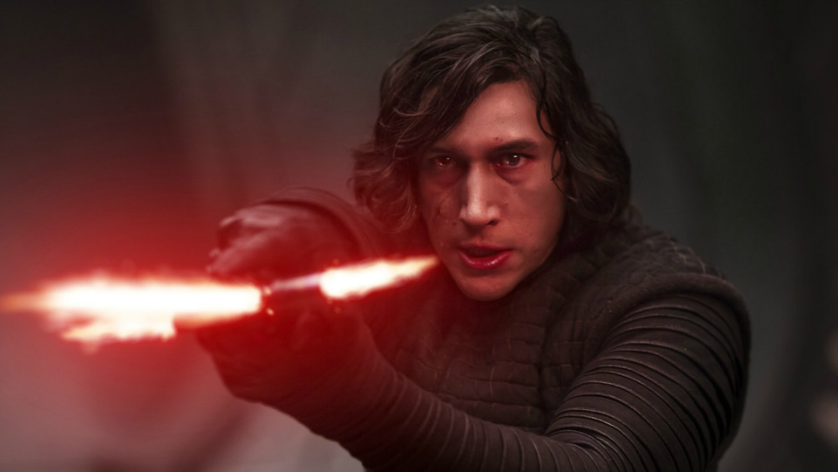 Adam Driver in Star Wars as Kylo Ren holding his red crossaber 