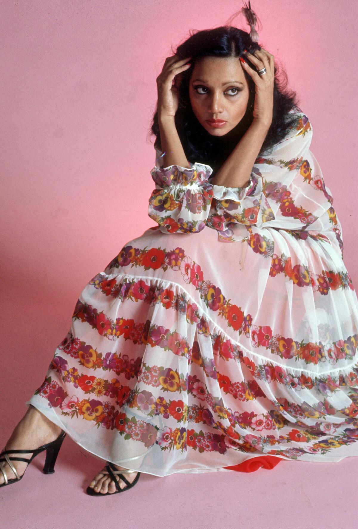 A woman sitting on the floor, wearing colorful clothing.