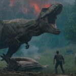 A T.Rex roars n front of an erupting volcano as a man looks on in Jurassic World: Fallen Kingdom