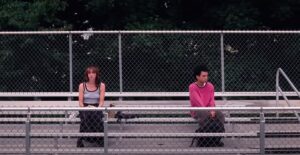 Super-awkward teenage sorta-friends Maddy (Brigette Lundy-Paine) and Owen (Justice Smith) sit far apart from each other on their school’s outdoor metal bleachers in I Saw the TV Glow