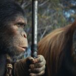 Noa (a chimp) and Raka (an orangutan) from Kingdom of the Planet of the Apes look at each other while Noa holds a weapon