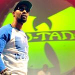 RZA in front of the Wu-Tang Clan logo