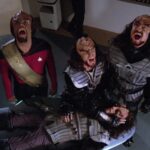 Worf and two other Klingons scream at the sky, while one of them closes the eyes of a fourth, fallen Klingon in Star Trek: The Next Generation