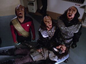 Worf and two other Klingons scream at the sky, while one of them closes the eyes of a fourth, fallen Klingon in Star Trek: The Next Generation