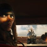 Anya Taylor-Joy as Furiosa in Furiosa, the Mad Max spinoff movie, looking back toward the camera with grease on her forehead.
