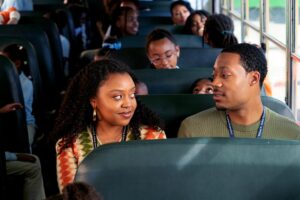 A man and woman sit together on a school bus looking at each other in a scene from "Abbott Elementary."