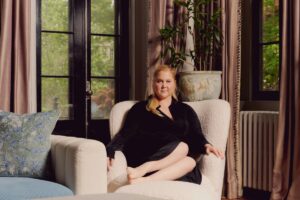 Amy Schumer curls up in a fuzzy chair for a portrait.