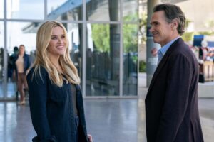 Reese Witherspoon and Billy Crudup chat in the lobby of a glass-walled building in "The Morning Show."