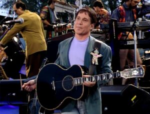 Paul Simon stands on a stage holding his guitar in a shot from "In Restless Dreams: The Music of Paul Simon."