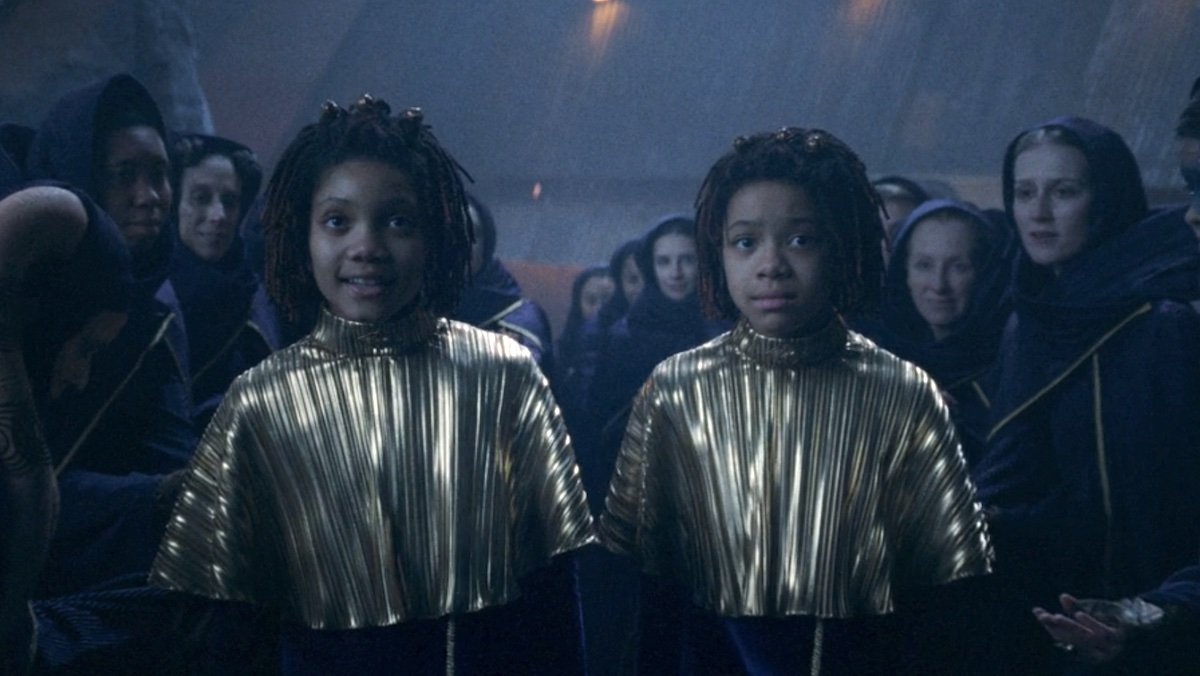 Twin girls in gold ponchos at night on The Acolyte