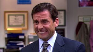 Steve Carell as Michael Scott, wincing exaggeratedly, in The Office.