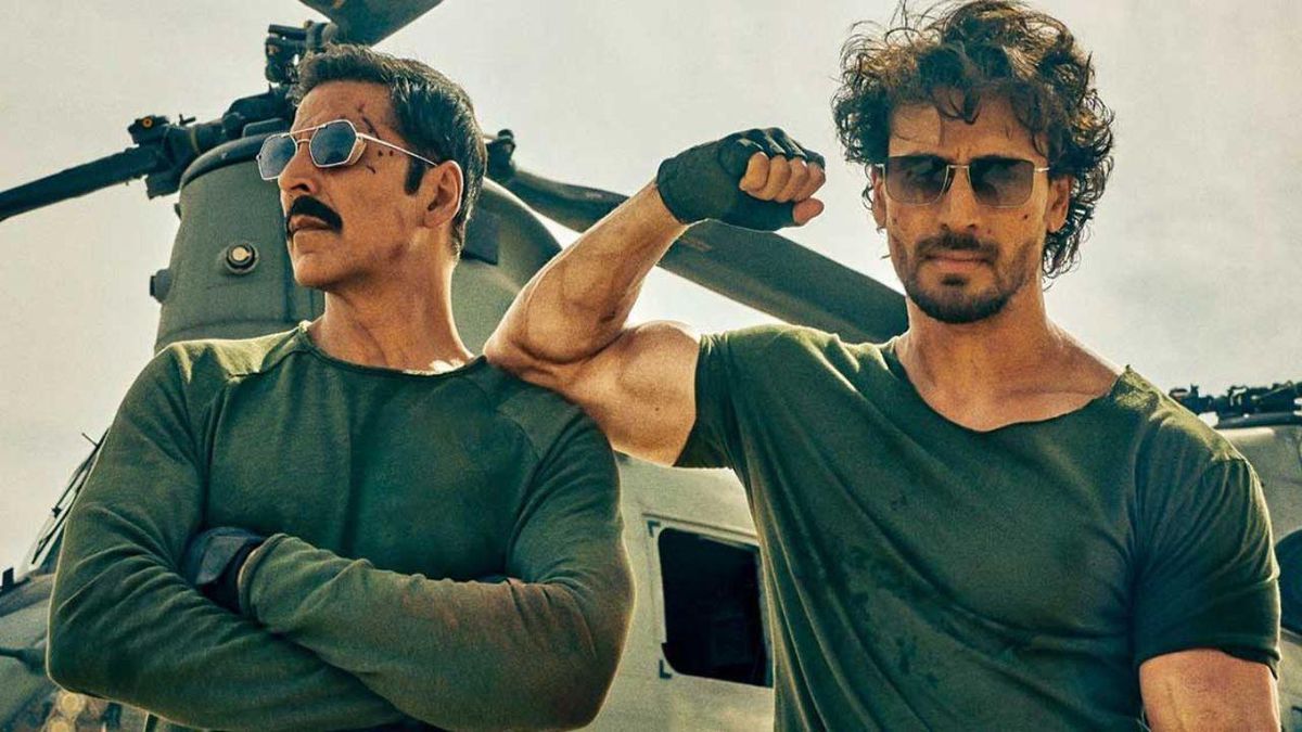 Tiger Shroff flexes his bicep, resting on Akshay Kumar’s shoulder, in front of a helicopter in Bade Miyan Chote Miyan. Kumar folds his arms.