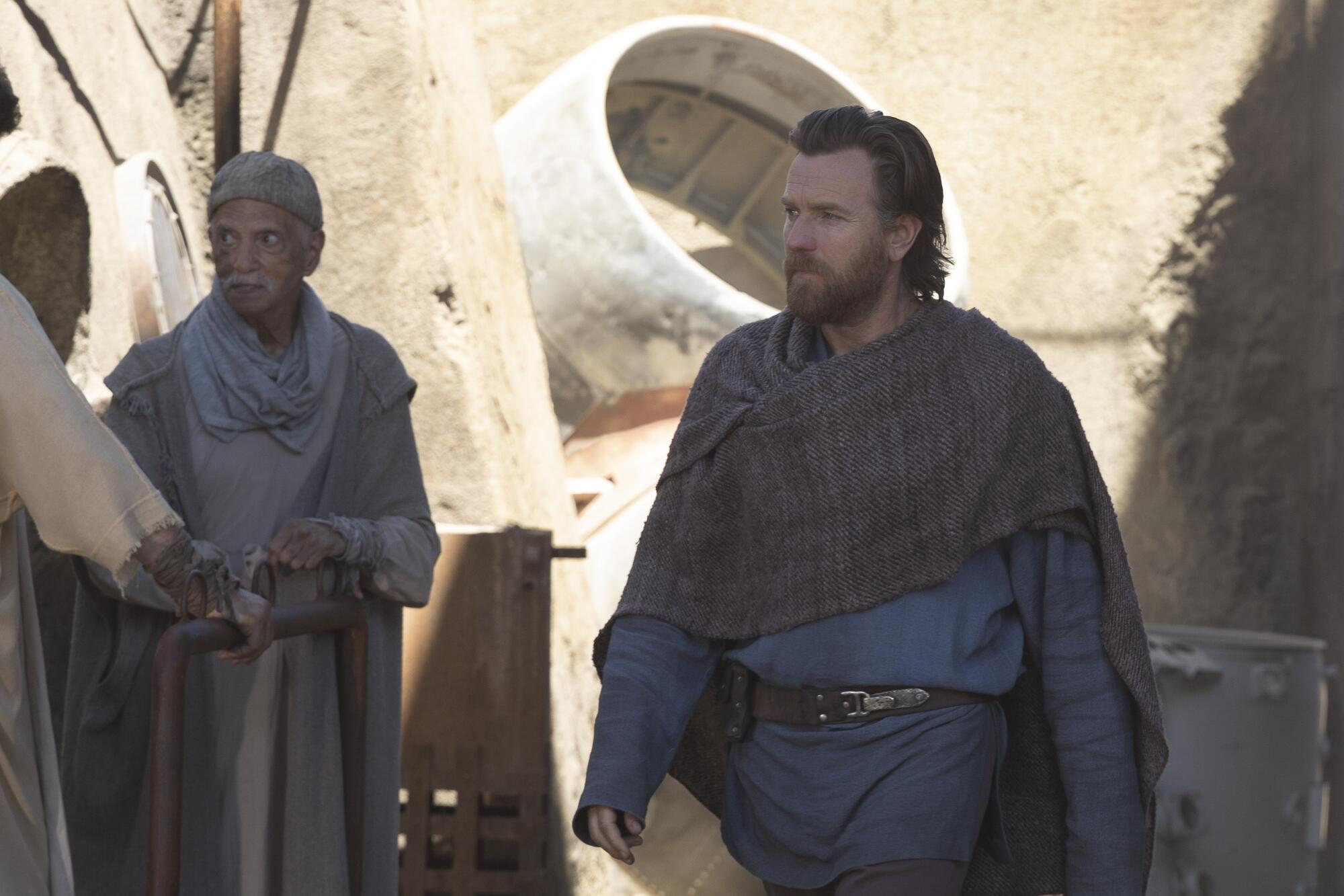 A bearded man walking through a town in the series "Obi-Wan Kenobi."