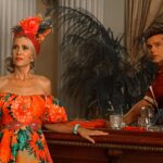 Kristen Wiig and Ricky Martin dressed in tropical patterns standing on either side of a bar in "Palm Royale."