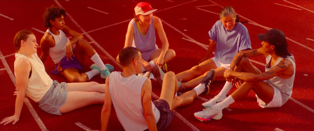 Several people sit on a track and have a conversation.