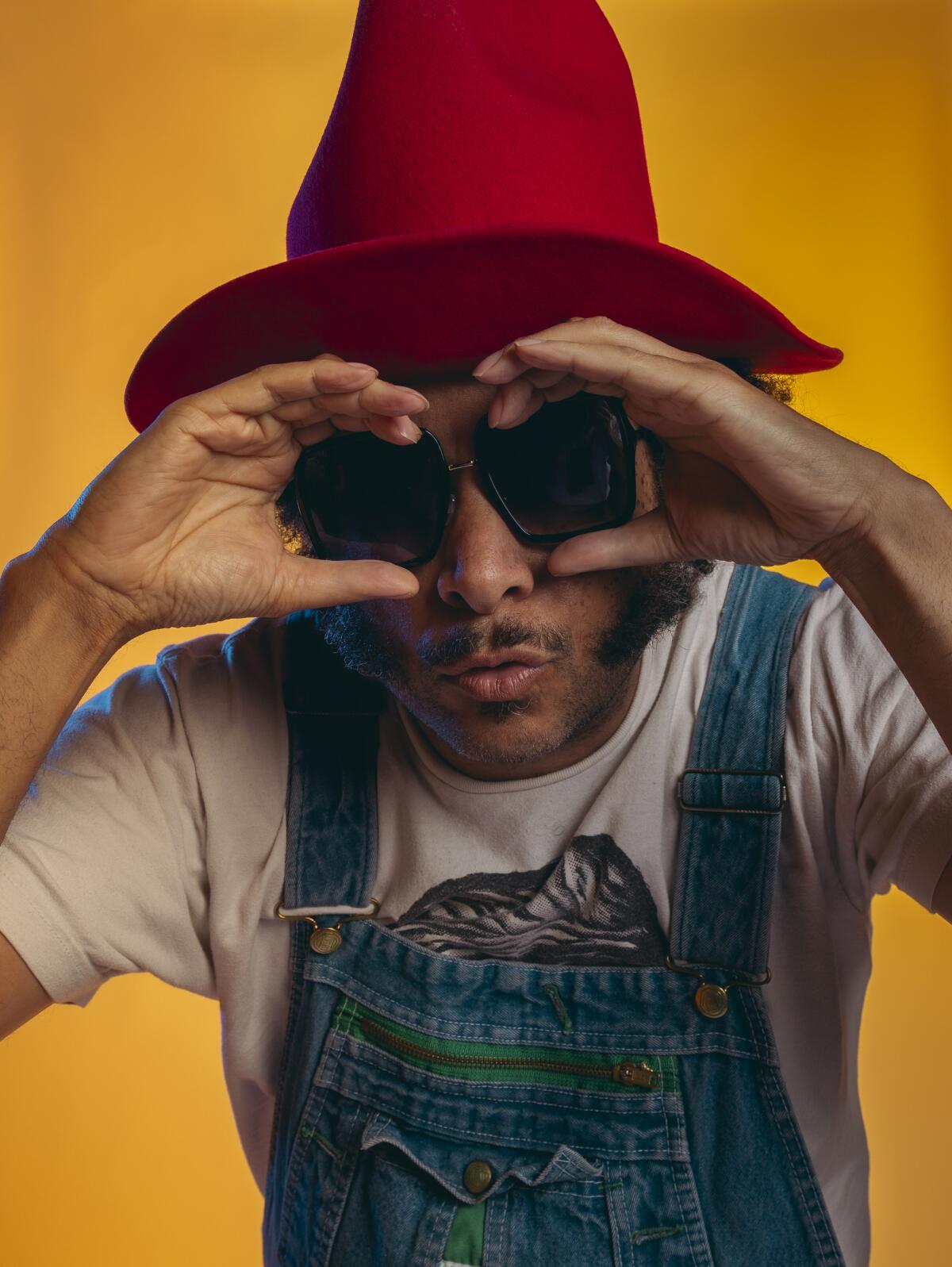 Boots Riley frames his dark glasses with his hands for a portrait.