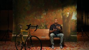 A man sits on a bench with a bicycle nearby in "Black Twitter: A People's History."