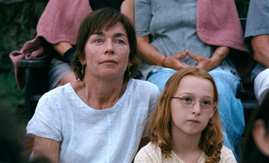 A mother and daughter watch an outdoor performance.