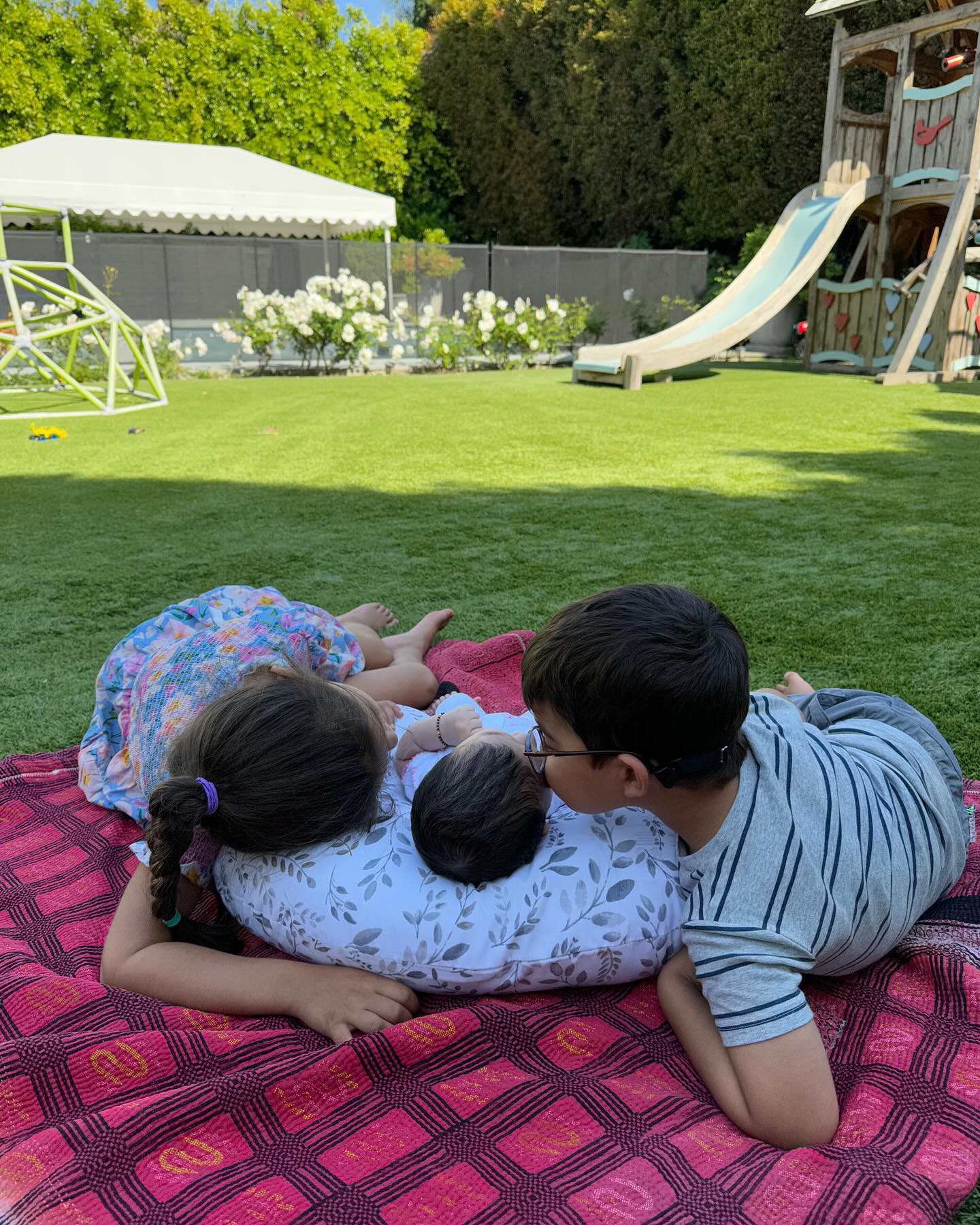 Mindy Kailing's three kids cuddling on a blanket in the backyard