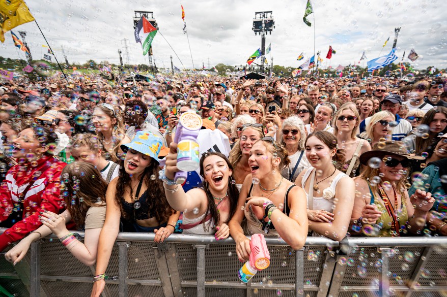 Music fans blow bubbles as they watch festival acts on the pyramid stage.