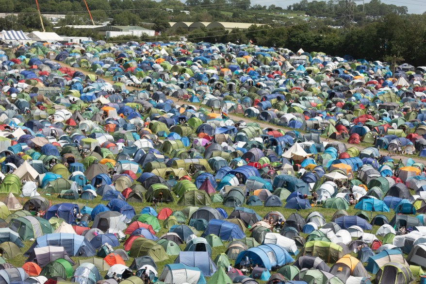 People walk around tents erected in the main camping fields.