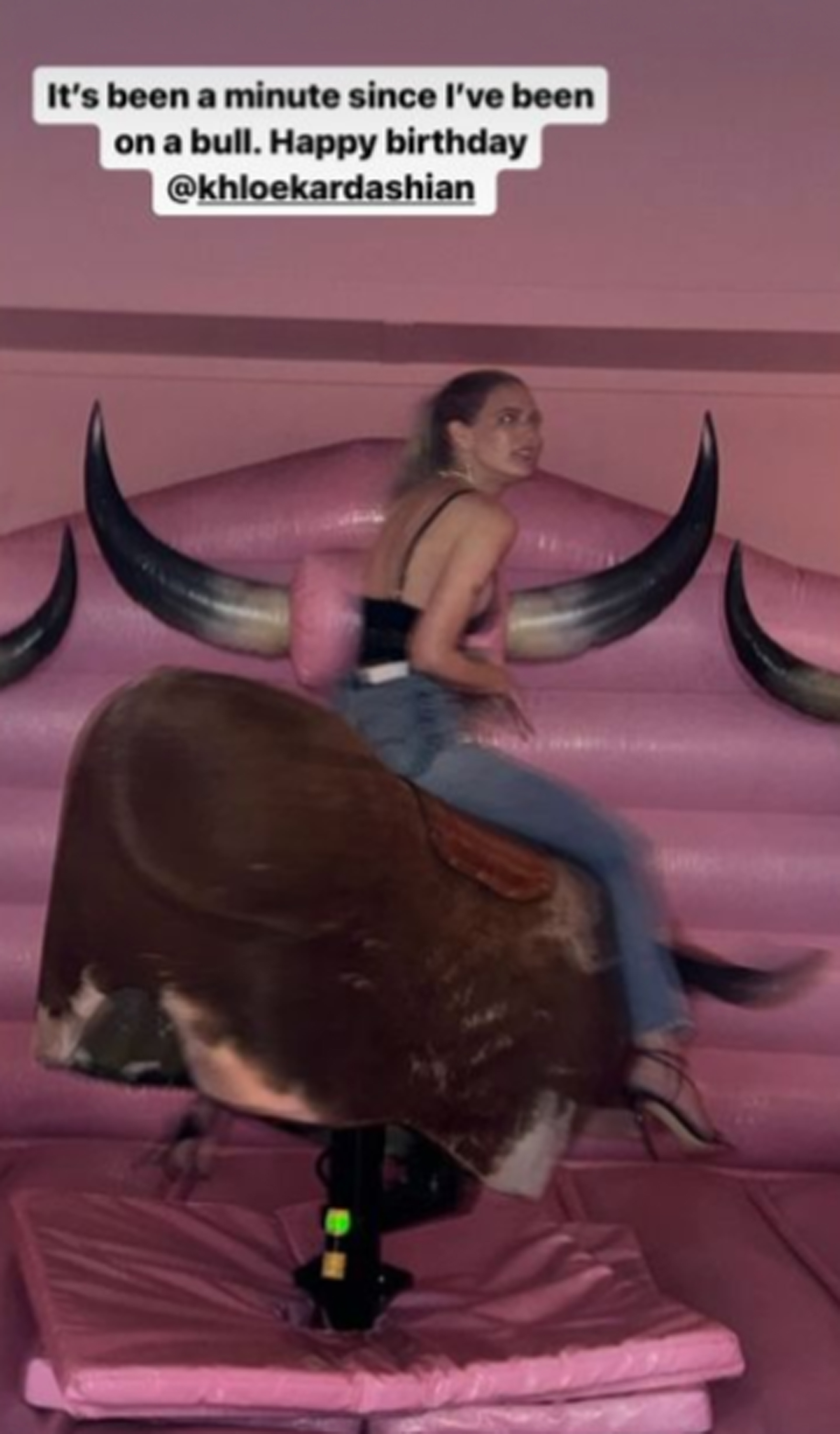 A guest at Khloe Kardashian's western-themed birthday party riding a mechanical bull