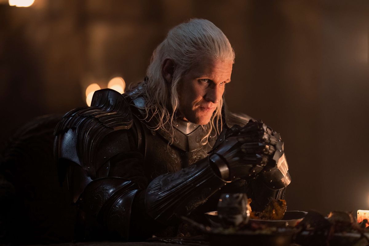 Matt Smith as Daemon Targaryen wearing armor and sitting at a table in House of the Dragon