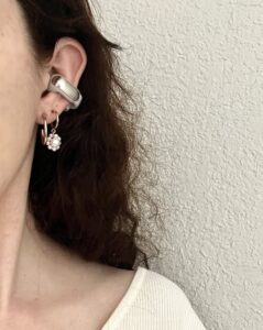 woman wearing Bose Ultra Open Earbuds on her ear styled with other earrings