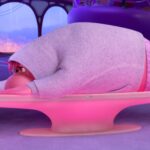 Embarrassment, a large, blobby, pink fellow in a grey hoodie, lies sprawled across the control board in emotions HQ as the other characters stand around looking worried in Pixar Animation Studios’ Inside Out 2